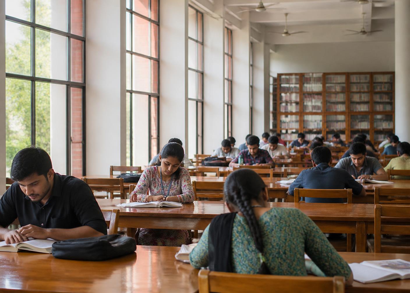 Students reading at long tables in a university library